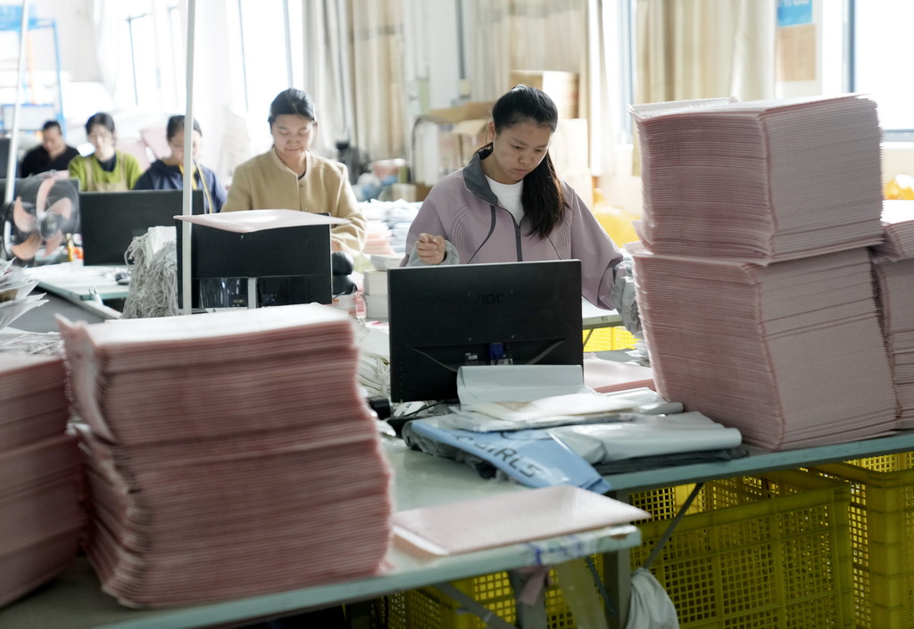 4月13日，织里镇一家童装企业的员工在仓储流水线上整理即将发货的童装产品。