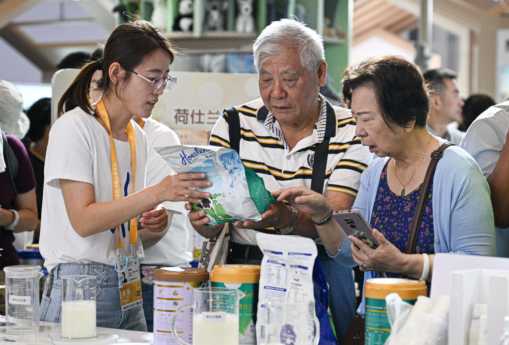 4月16日，参展商在第六届消博会现场向观众介绍新西兰品牌奶粉。新华社记者 蒲晓旭 摄