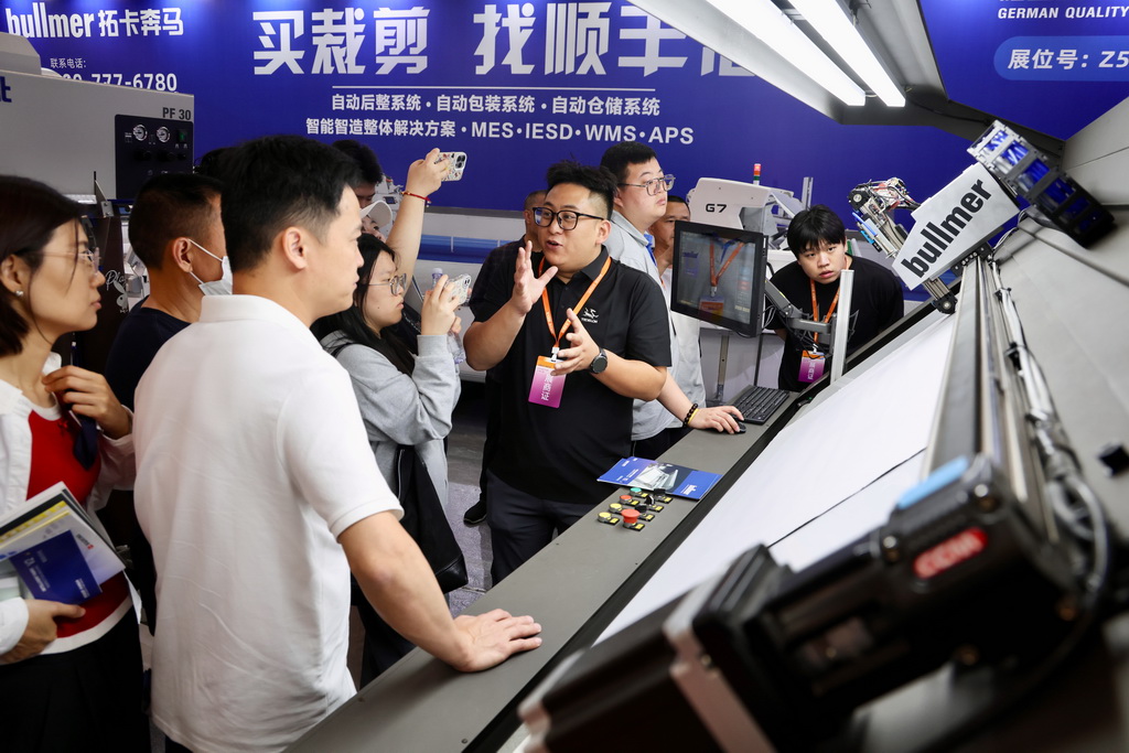4月18日，参展商工作人员在博览会上向参观者介绍智能裁剪设备。