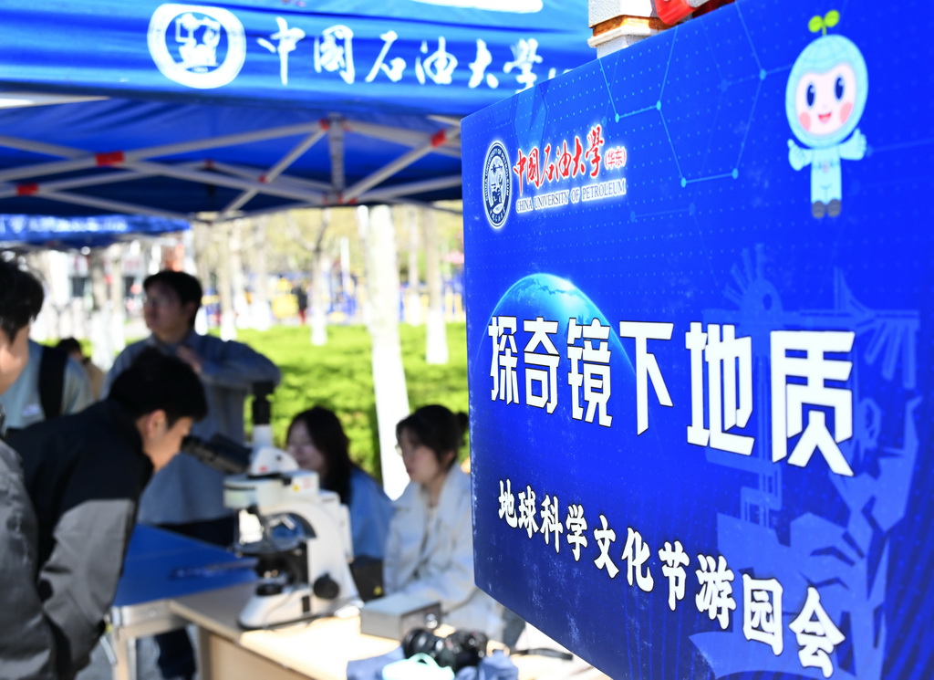 4月19日，游园参与者在地球科学文化游园会上通过显微镜观看地质样本。