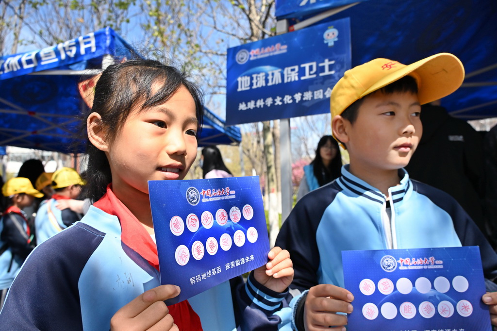 4月19日，小学生在地球科学文化游园会上展示打卡徽章。