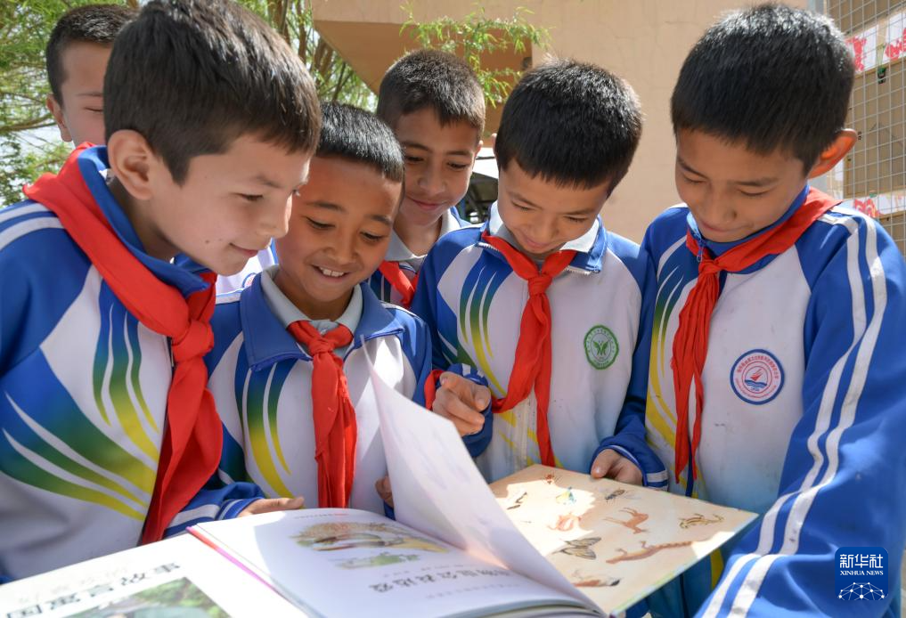 4月21日，在新疆新和县依其艾日克镇木纳尔村小学，小朋友们在“图书巴扎”上阅读图书。