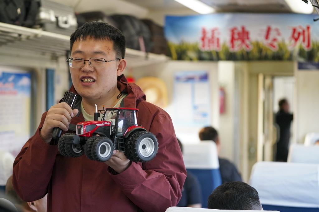 5月13日，一名农技人员在K5153次“插秧专列”上为乘客讲解农机操作技术与设备运维知识。