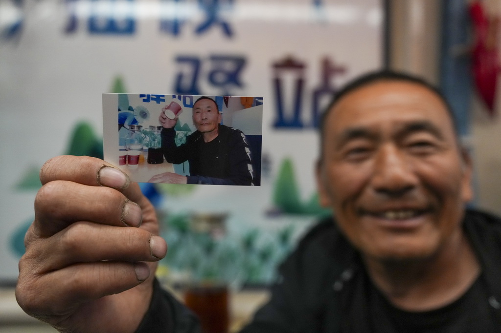 5月13日，乘客在K5153次“插秧专列”上展示列车员为自己拍摄的照片。