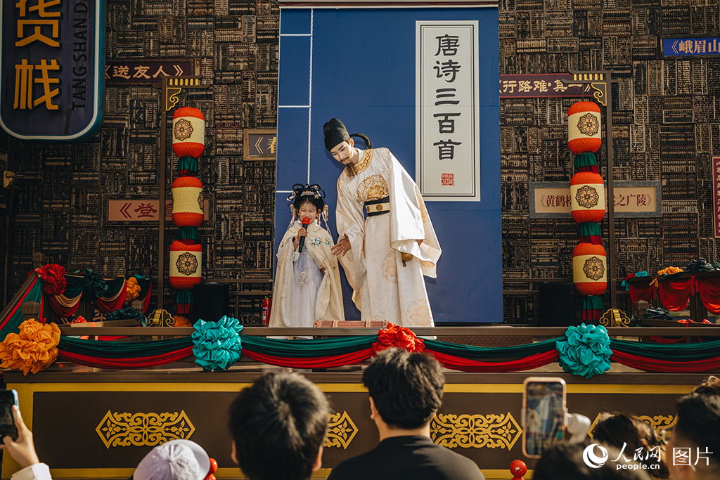 2026年5月18日，河北唐山河头老街的NPC演员“李白”正与小游客吟诗互动。人民网记者 商帆摄