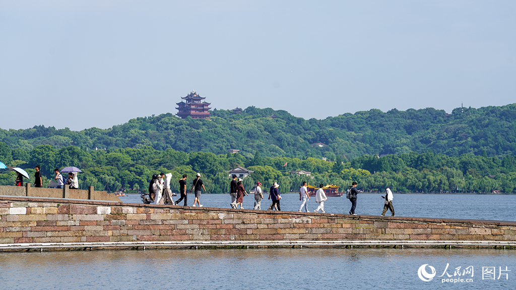 2026年5月18日，在浙江杭州西湖景区，游客们泛舟湖上、漫步白堤，乐享品质旅游的美好时光。人民网记者 郭扬摄