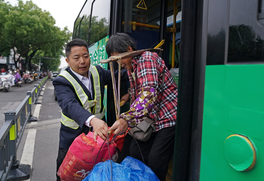 在“菜農專線”公交位於南昌市市區的站點，公交安全員協助菜農下車（5月9日攝）。