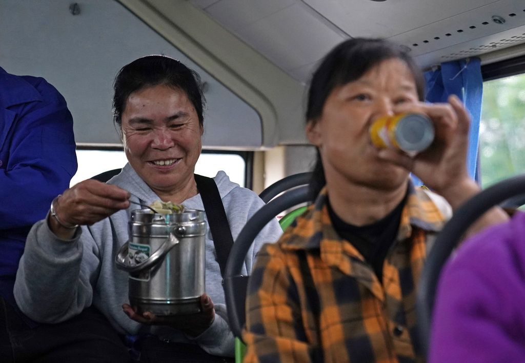 在“菜農專線”公交車上，菜農江長花吃起了早飯（5月9日攝）。