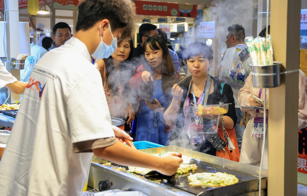 5月21日，观众在文博会现场挑选品尝美食。