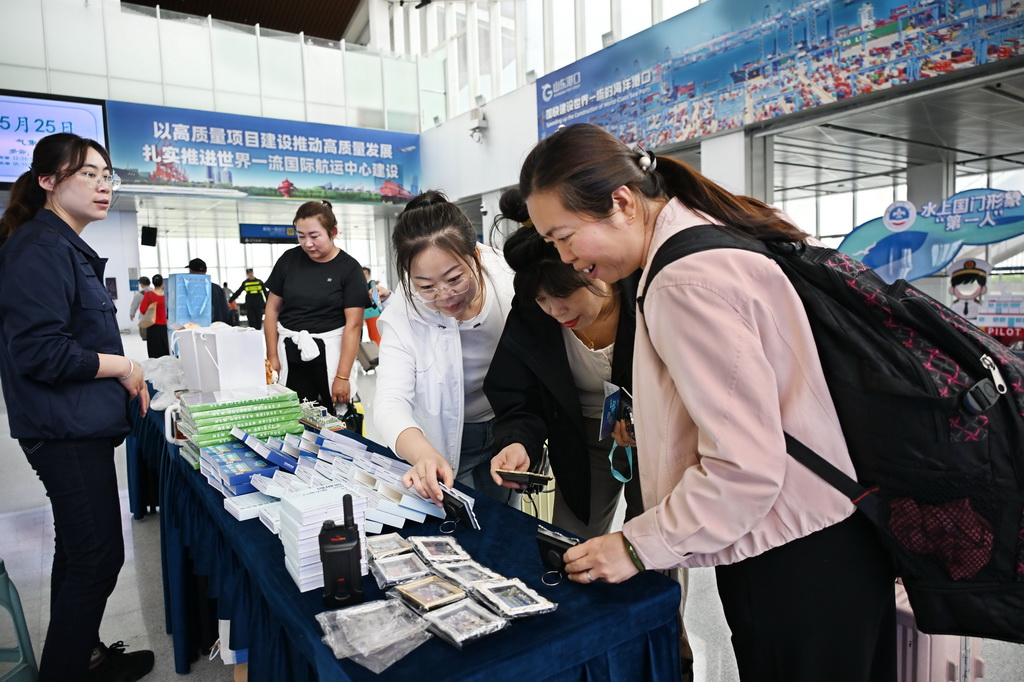 5月25日，游客在青島郵輪母港候船大廳選購郵輪文創商品。