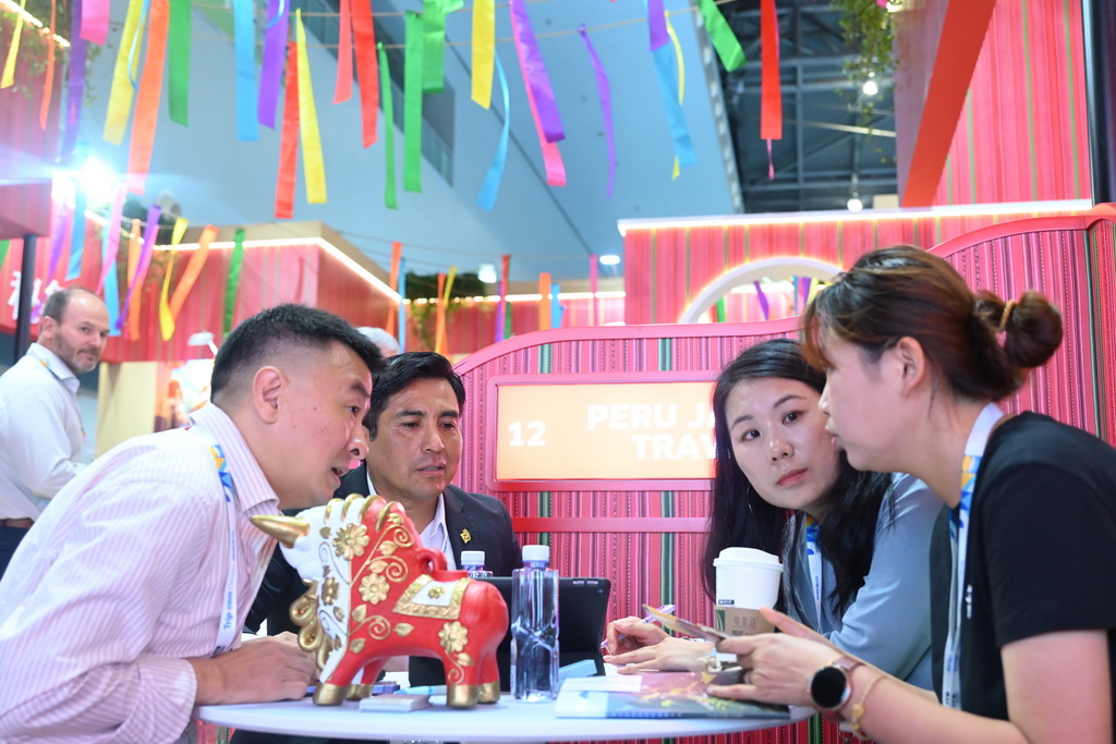5月26日，在秘鲁展台，专业观众与展商洽谈。