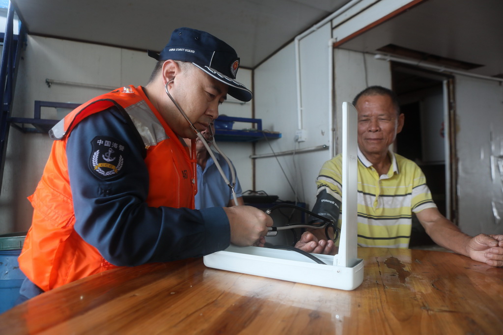 5月23日，中国海警东安舰执法员为渔民测量血压。
