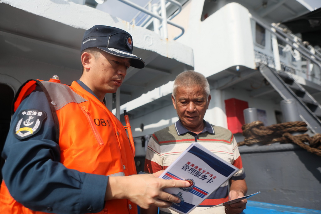 5月23日，中国海警东安舰执法员为渔民进行普法宣传。