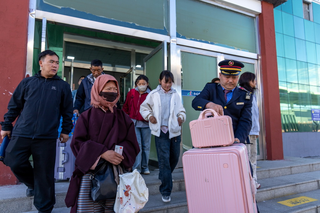 6月14日,在那曲站,客运值班员王志先帮旅客拿行李。
