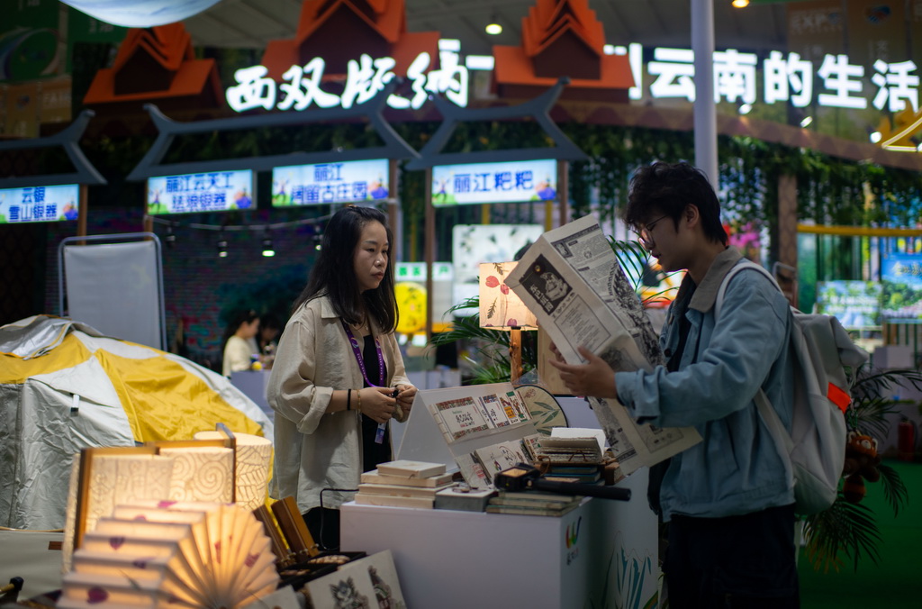6月16日，游客在第10届中国—南亚博览会现场了解一张用东巴纸制作的纸图。
