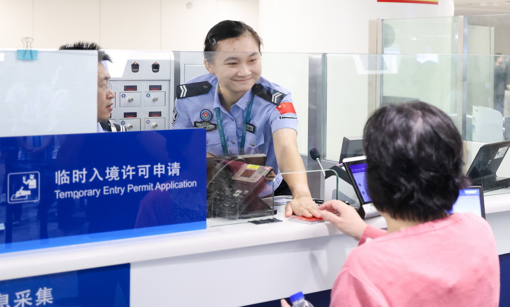 海口美兰边检站民警为入境旅客办理边检手续(6月17日摄)。新华社记者 杨冠宇 摄