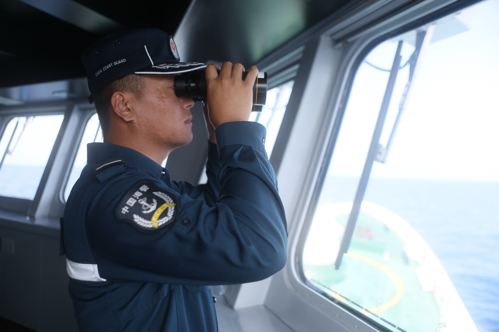 6月6日，中国海警东安舰执法员李磊在驾驶室瞭望海面情况。