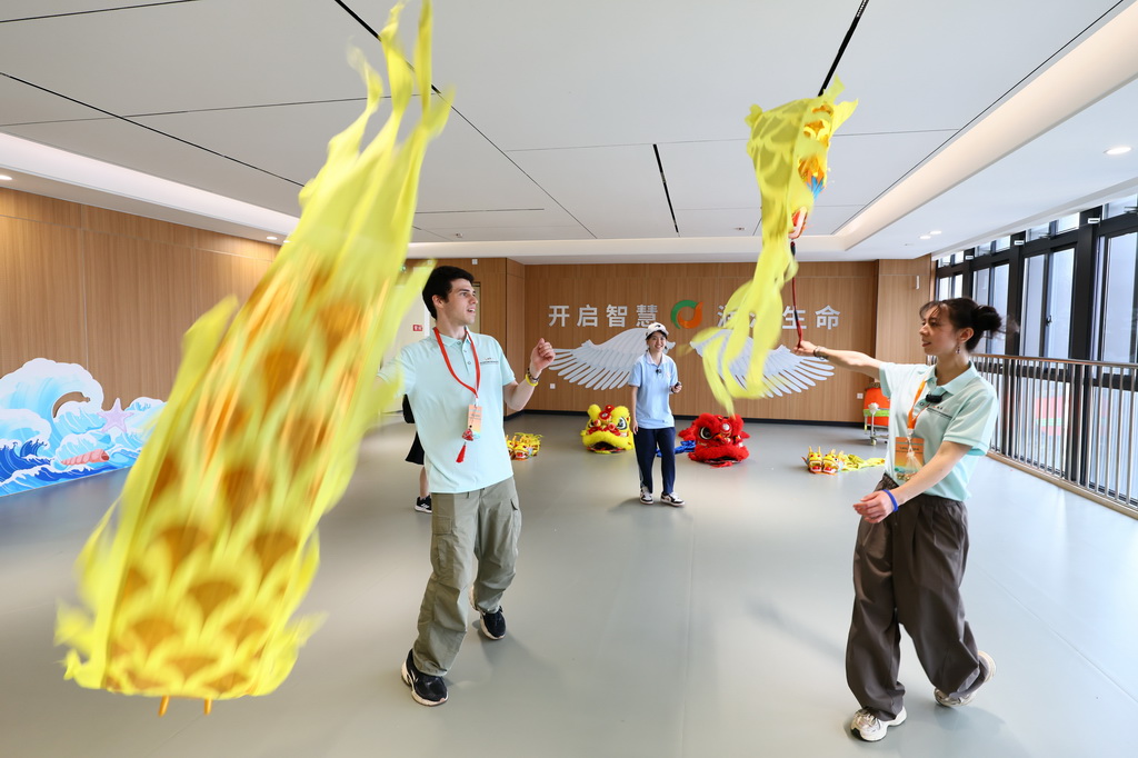 6月30日,在福州屏东中学举行的飞虎队友谊学校师生进校园活动上,美国青年在挥舞彩带龙。