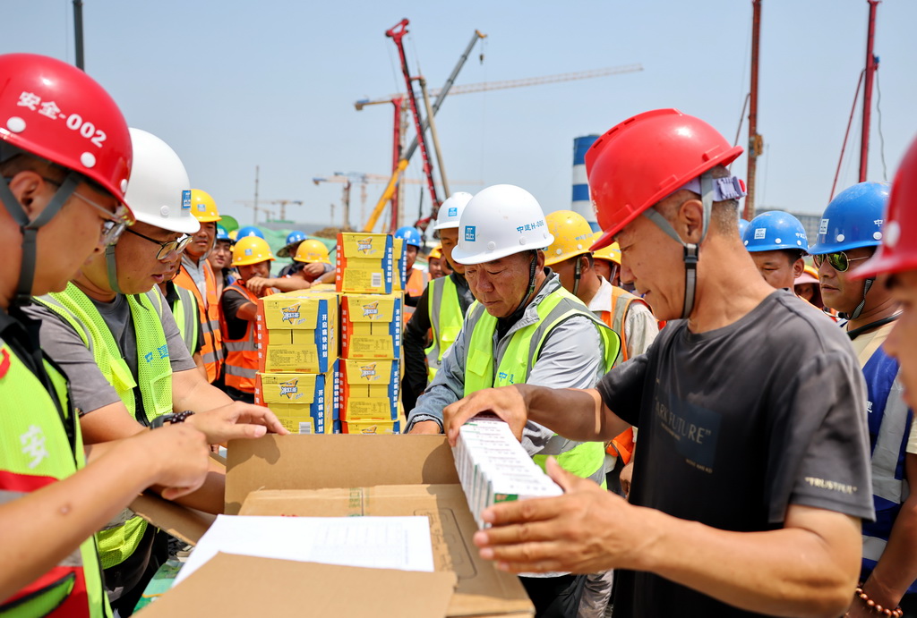 7月2日，中建二局项目管理人员在给工人发放防暑物资。