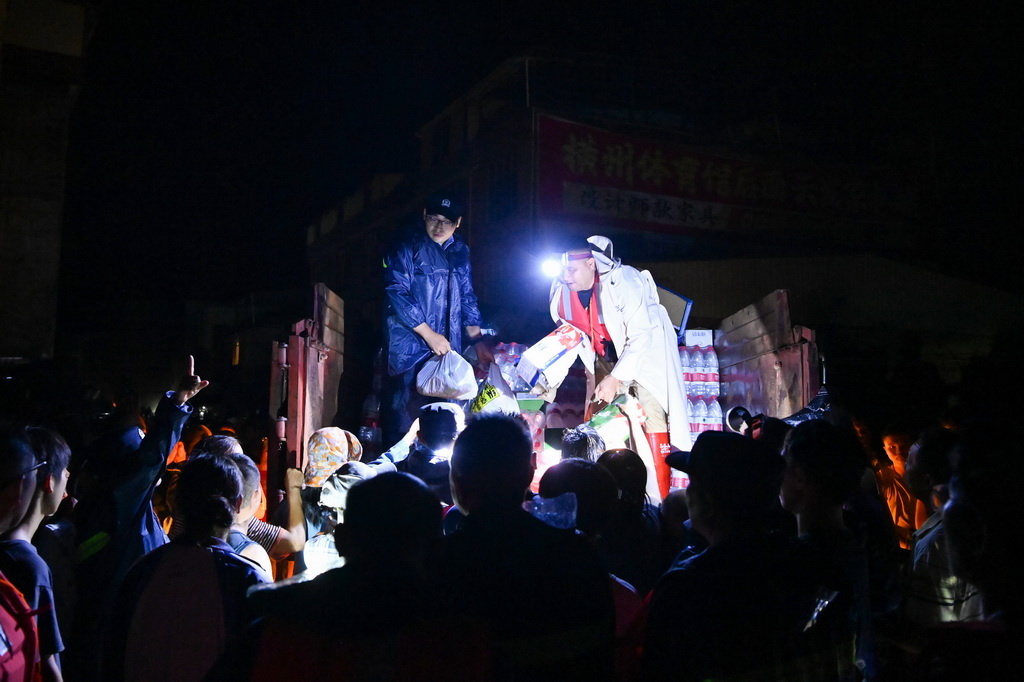 7月6日，在广西南宁横州市校椅镇六蓝村，救援人员在分发物资。