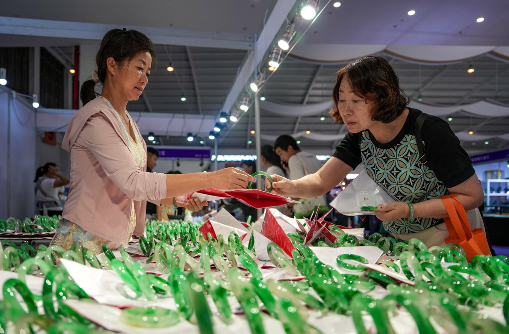 7月9日，一名顾客（右）在昆明石博会上挑选手镯。