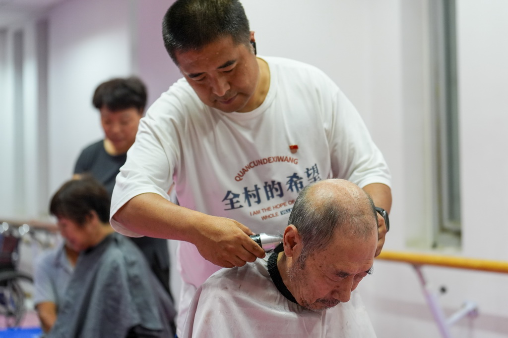 7月11日，群众在北京市平谷区体育中心安置点接受免费理发服务。该安置点目前接收了平谷区镇罗营镇8个村庄的近500名村民。