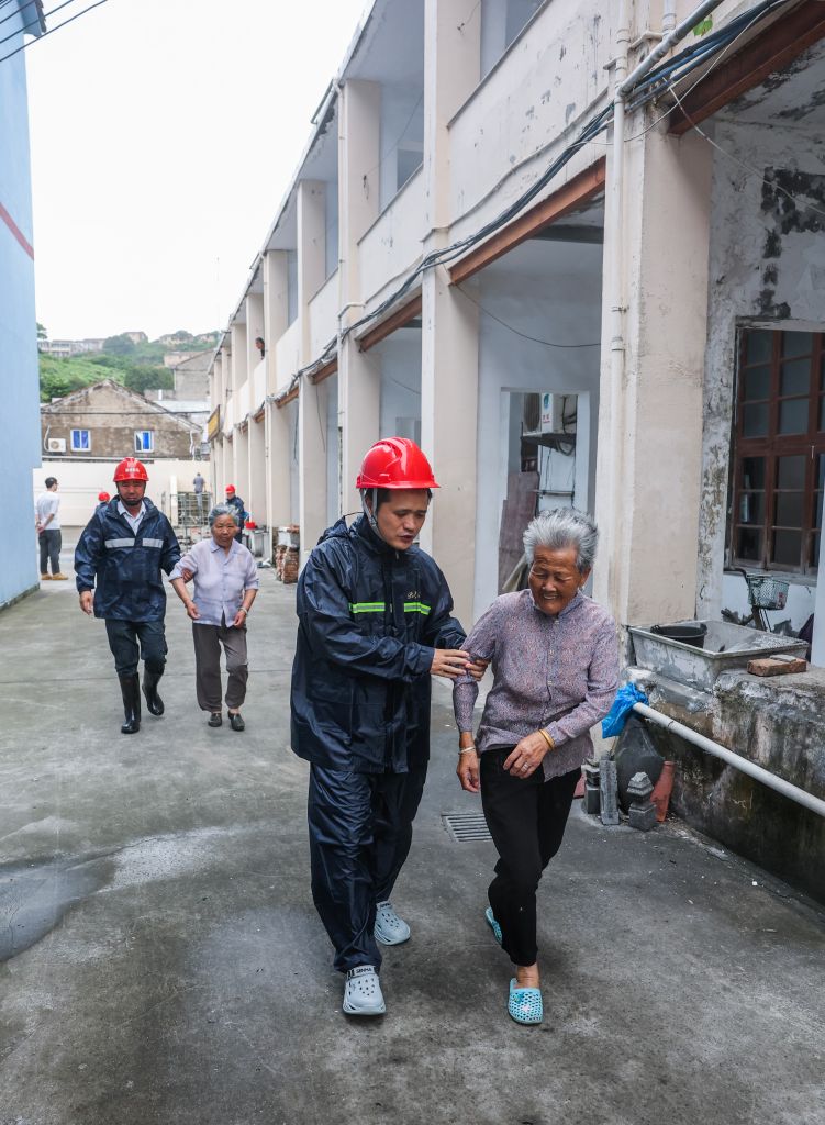 7月11日，浙江台州温岭石塘镇杨柳新村的村干部和党员志愿者带领独居老人前往避灾安置点。新华社记者 徐昱 摄