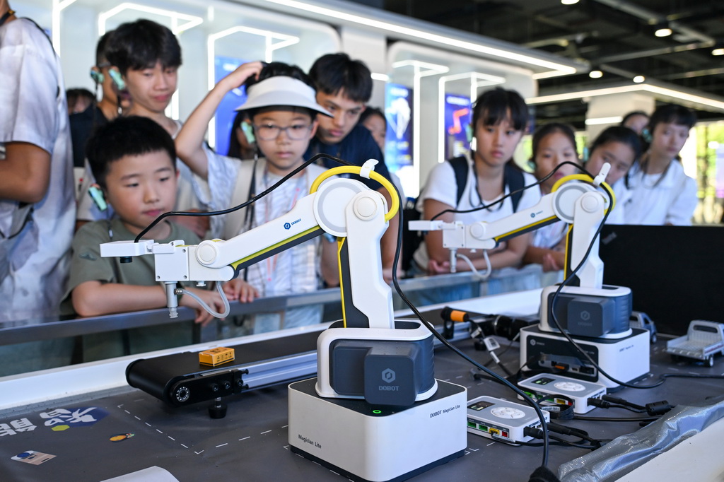 7月11日，两岸青少年在重庆机器人AI应用展示中心观看工业机器人模型演示。