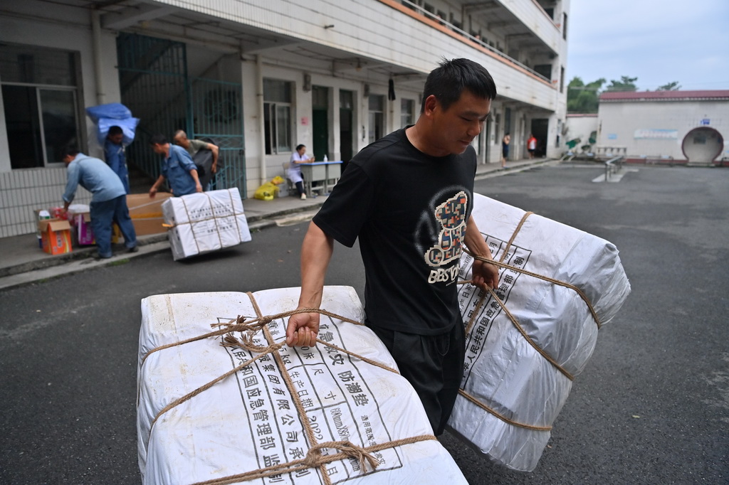 一名志愿者在广西贵港市覃塘区覃塘三中安置点搬运救援物资（7月8日摄）。新华社记者 周华 摄