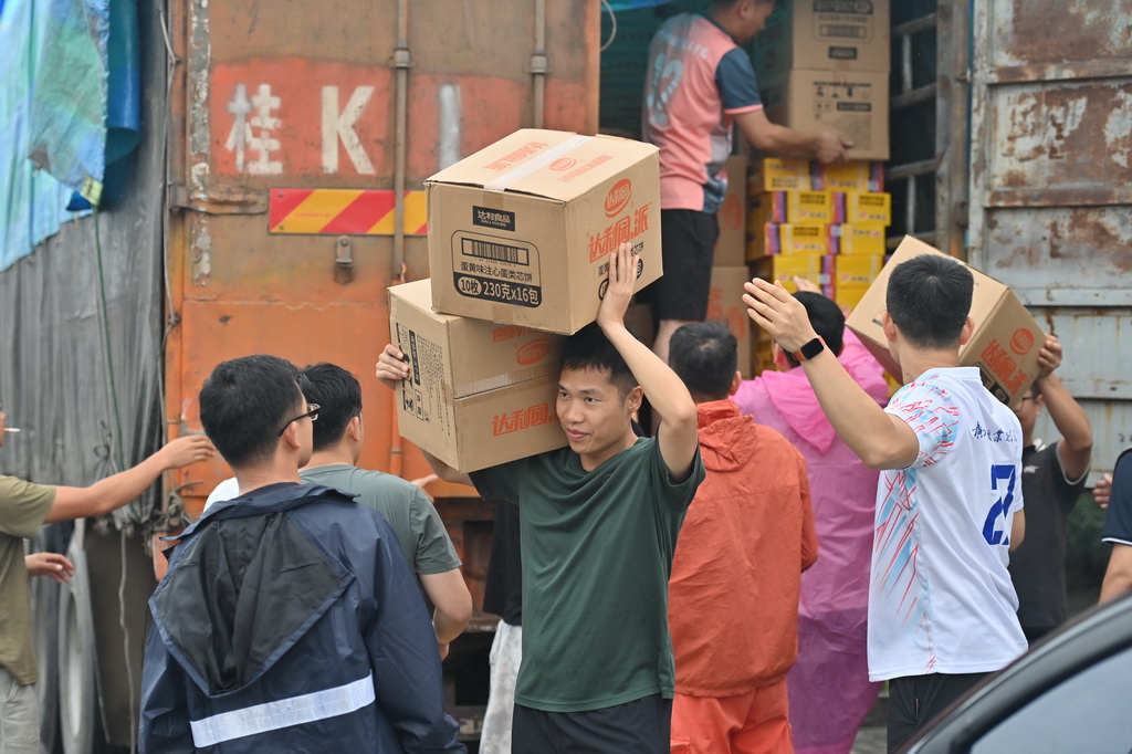 志愿者在广西贵港市西江教育园区搬运救援物资（7月8日摄）。新华社记者 周华 摄