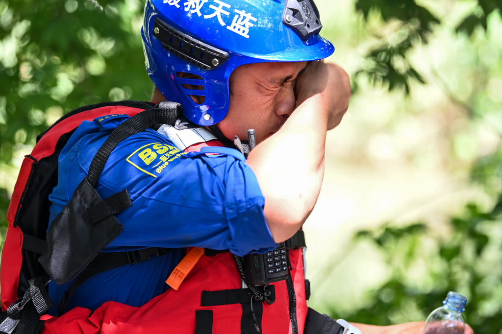 7月10日，在广西贵港市的救援现场，一名救援人员在擦拭面部的汗水。新华社记者 曹祎铭 摄