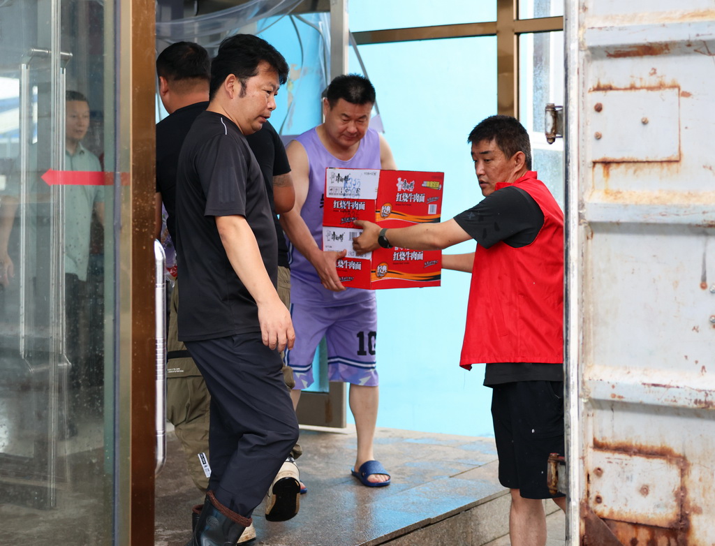 7月14日,党员干部在铁岭开原市靠山镇中学安置点搬运物资。新华社记者 韩赫 摄