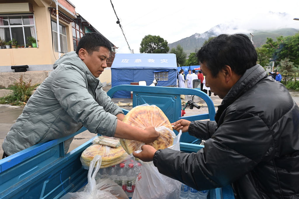 7月16日，在麻当镇“7·13山洪灾害”临时安置点，村民在为清淤人员准备午饭。新华社记者 范培珅 摄