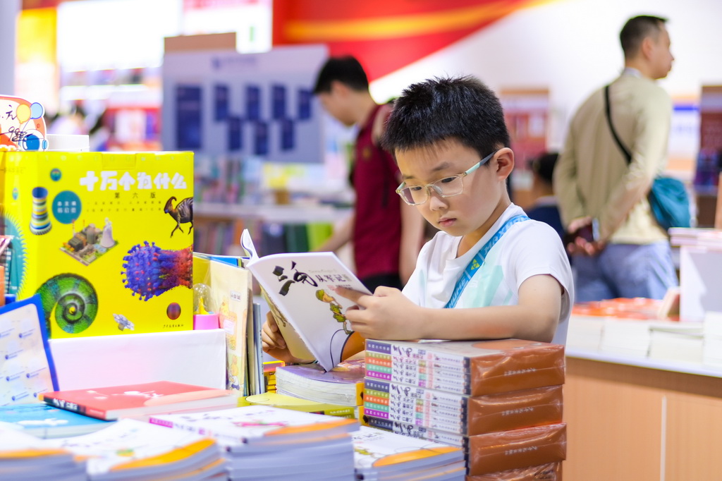 7月24日，小读者在第34届全国图书交易博览会上海展区阅读书籍。