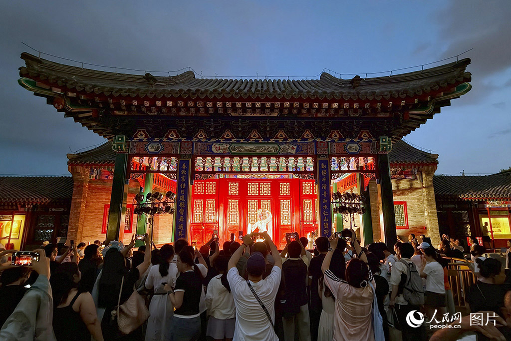 7月24日晚，沈阳故宫暑期夜场开放，游客驻足欣赏京剧演出。此次暑期夜场即在保障文物安全前提下，通过“夜游+演艺+互动”复合模式，为海内外游客提供夏夜文化之旅。人民网记者 周颂雪摄