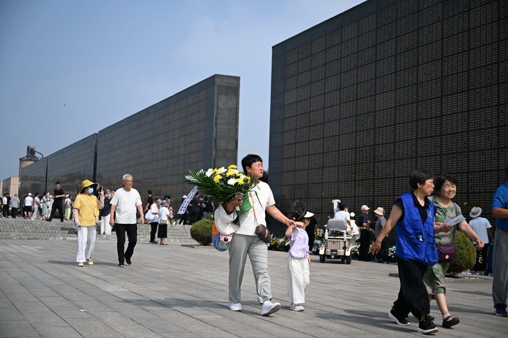 7月28日，市民手捧鲜花前往唐山大地震罹难者纪念墙祭奠。新华社记者 牟宇 摄