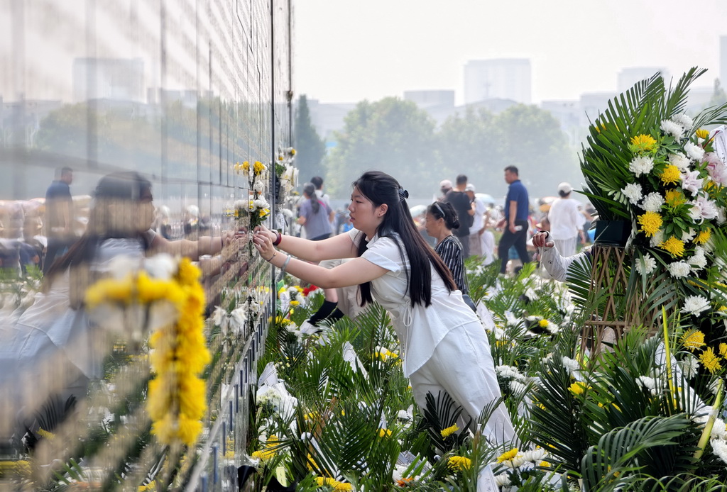 7月28日，市民将鲜花贴在遇难亲人的名字附近，表达哀思。新华社记者 杨世尧 摄