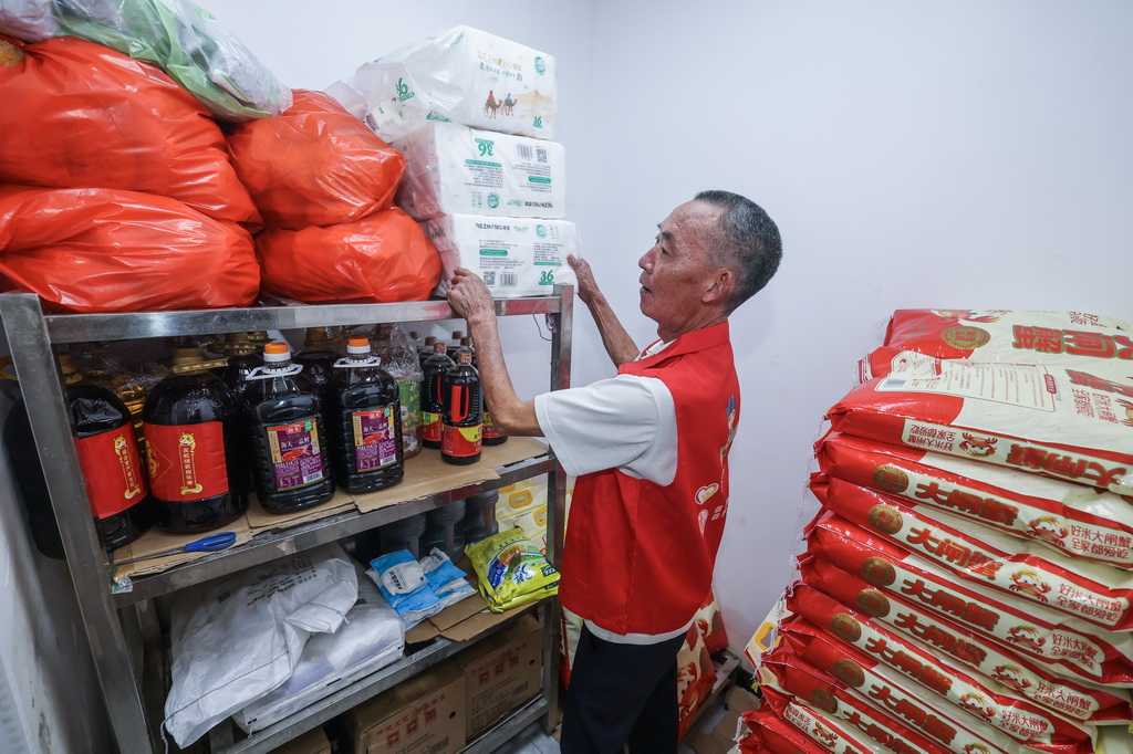7月28日,荻浦村老年食堂的银发志愿者在老年食堂仓库清点捐赠的米面油盐等物资。