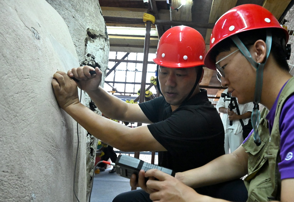7月29日,专业技术人员在河南浚县大伾山摩崖大佛修缮现场开展工作。