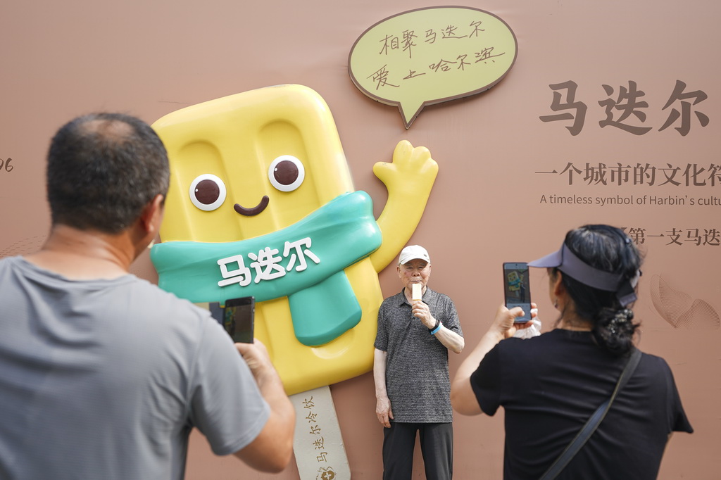 7月22日，人们在哈尔滨中央大街马迭尔品牌打卡装置前合影留念。新华社记者 那宇奇 摄
