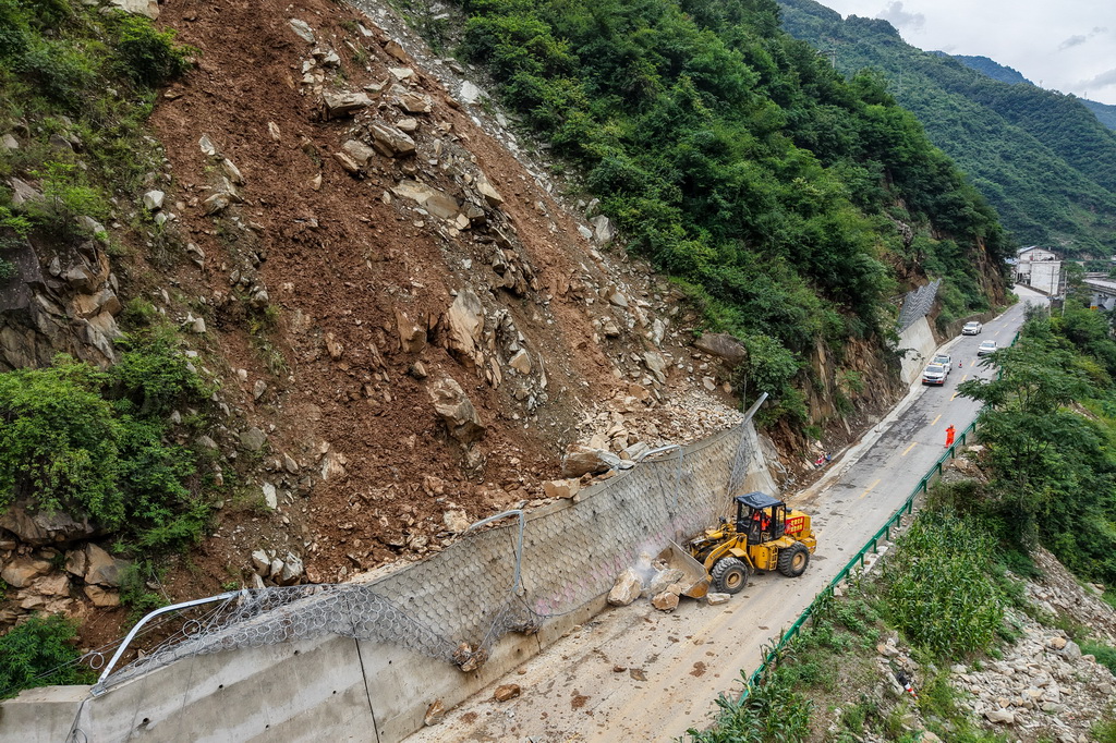 8月2日，在陇南市武都区枫相乡草坪村，公路抢险人员清理省道S206线塌方落石（无人机照片）。