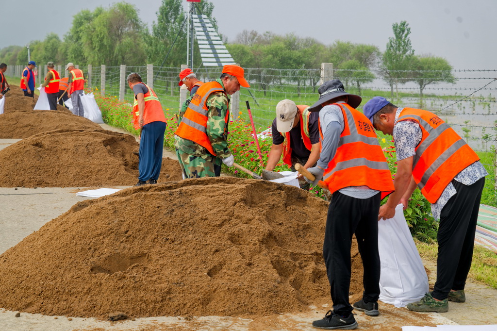 8月6日，在黑龙江同江市滨江路段，同江市农村公路养护中心的工人在装沙袋。