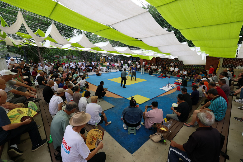 人们坐在天津市红桥区跤场口袋公园多层看台上观看摔跤表演（7月26日摄）。