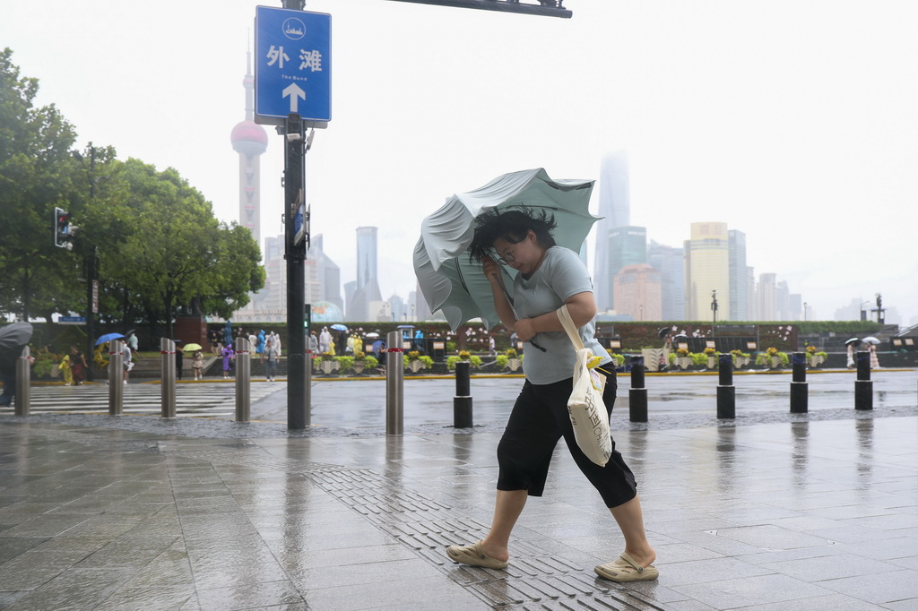8月9日，在上海黄浦区南京东路上，人们冒雨前行。