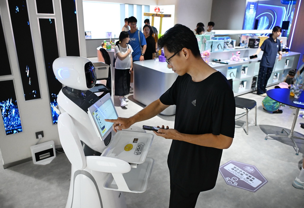 8月11日，一名男子在青岛机器人6S体验店与售卖机器人互动。