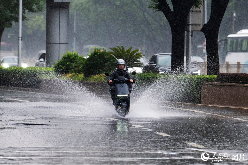 2026年8月12日，北京国贸，行人在暴雨中行进。