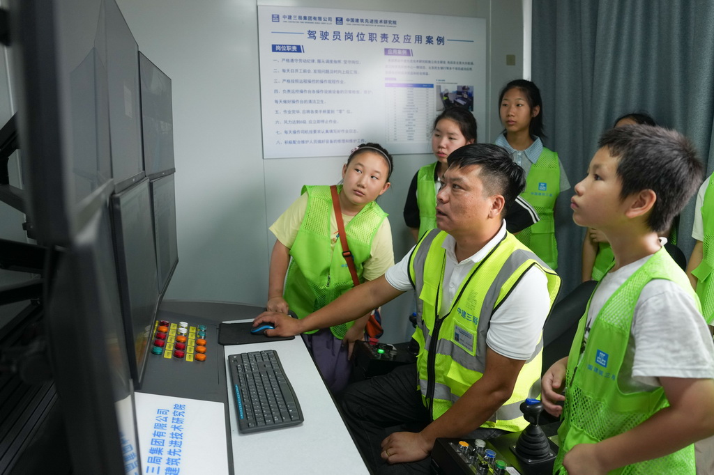 8月13日，“小候鸟”们在项目工地观摩工程技术人员操作远程驾驶智能集控数字塔机。