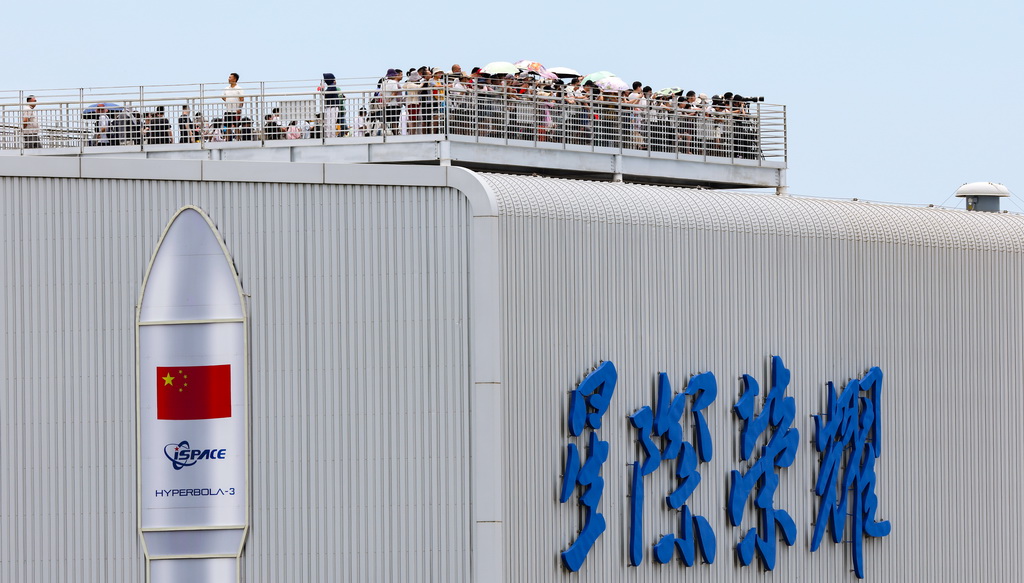 7月10日，游客在海南省文昌市龙楼镇一处参观点观看火箭发射。新华社记者 杨冠宇 摄
