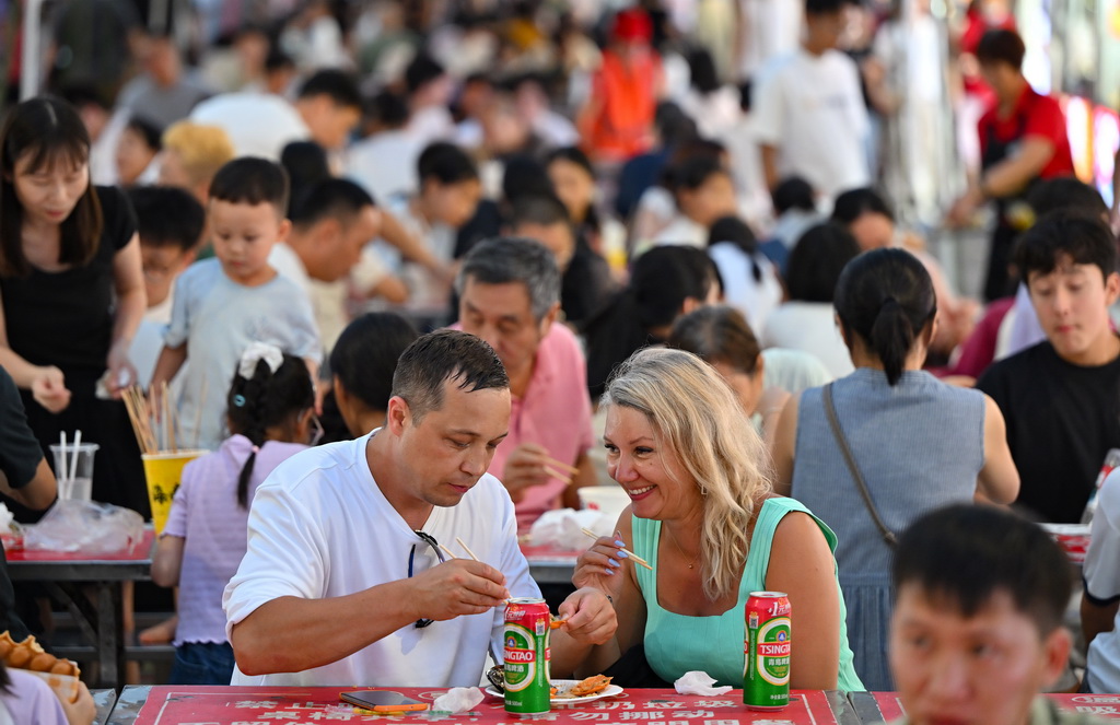 7月17日，游客在海口海大南门夜市品尝美食。新华社记者 郭程 摄