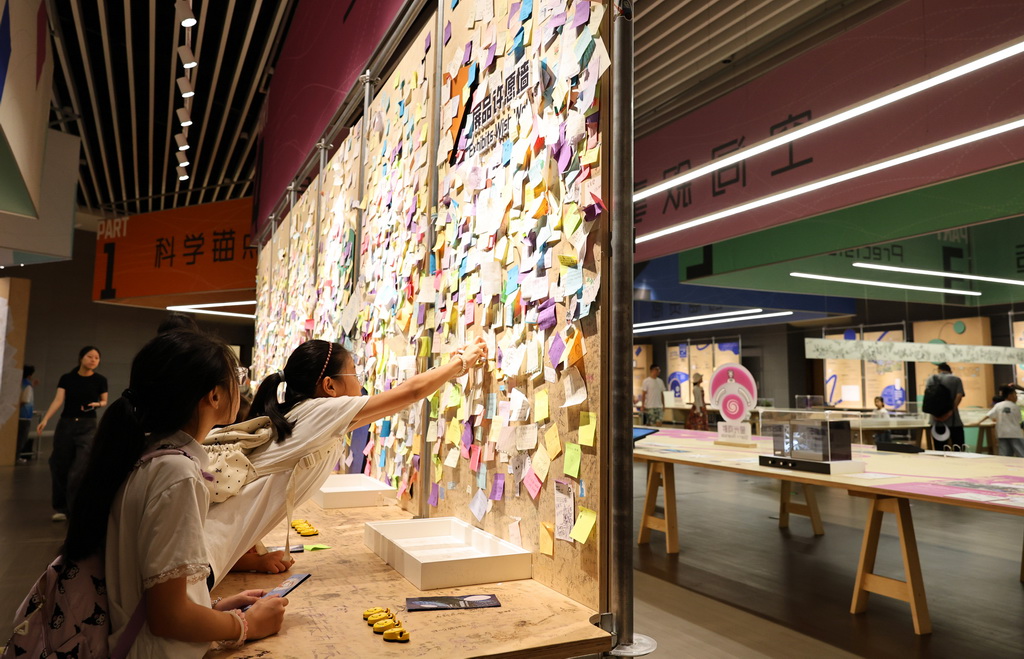8月18日，参观者在“从零到无穷 科技馆展品诞生记”展厅内设置的展品许愿墙前张贴自己写下的愿望。